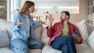 womensway 141 Egy pár vitázik a kanapén, a nő dühösen gesztikulál, a férfi védekezően reagál.