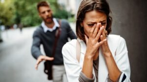 Egy nő szomorúan takarja el az arcát, míg egy férfi hátrafelé nyújtja a kezét.