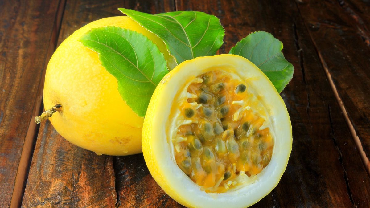 Érett passiógyümölcs, fényes sárga héjjal és zöld levelekkel, félbevágva.