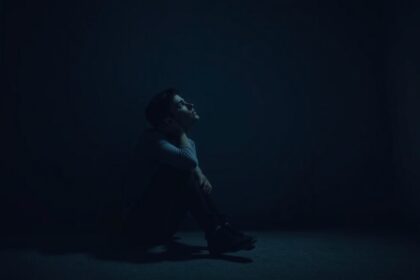 Egy fiatal férfi szorongva ül egy sötét szobában.