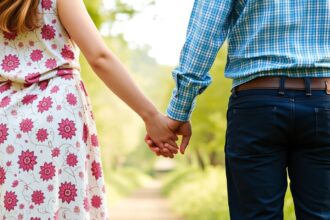 Egy pár kézen fogva sétál egy zöld pázsiton, a kapcsolat erősítésének szimbóluma.