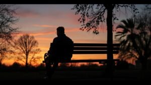 womensway 139 Férfi ül egy padon naplementekor, mély gondolatokkal