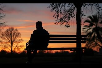 Férfi ül egy padon naplementekor, mély gondolatokkal