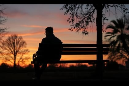 Férfi ül egy padon naplementekor, mély gondolatokkal