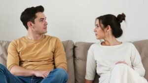 Fiatal pár ül a kanapén, érzelmi távolság a kapcsolatukban.