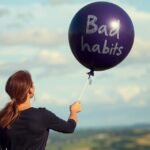 Nő, aki egy lila lufit tart a kezében, ami a romboló szokásokra utal.