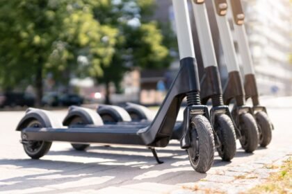 Elektromos roller parkolóban, zöld fákkal körülvéve